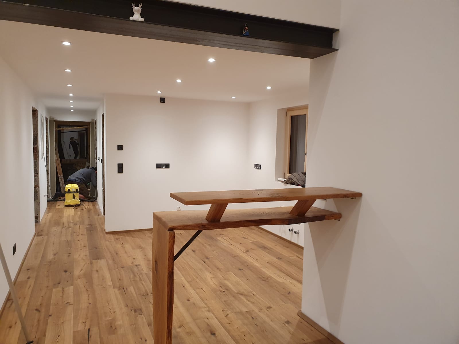 Innenraum mit maßgefertigtem Holzsteg und sichtbarem Deckenbalken
